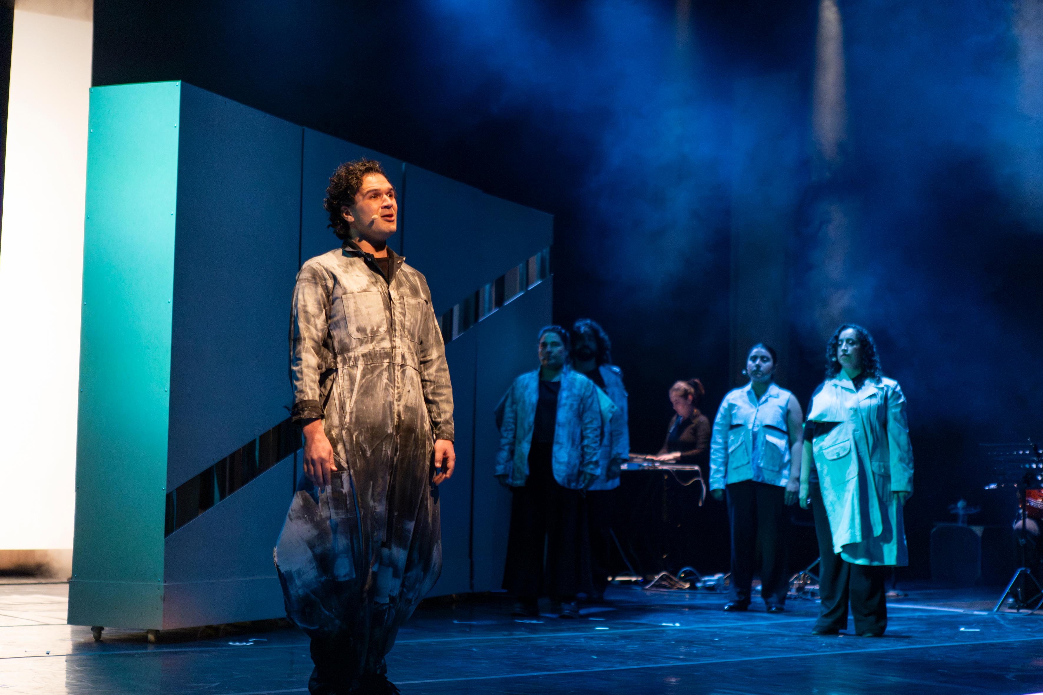 Blue-lit multidisciplinary stage performance.